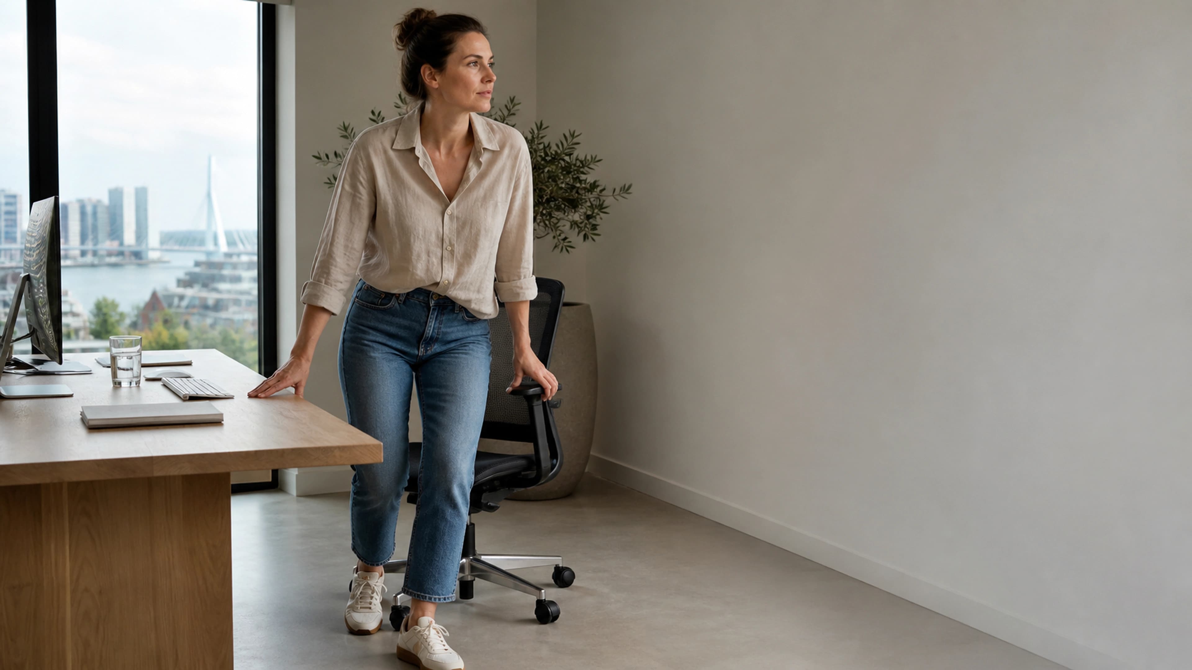 Desk worker rising carefully from a chair to begin a short movement break in a bright home office