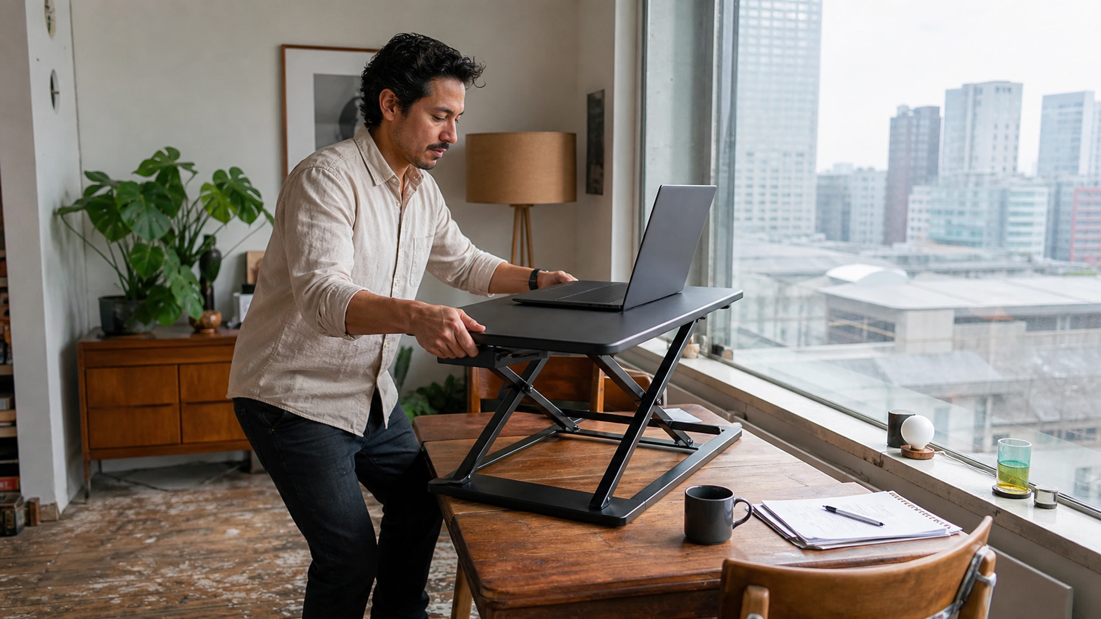 Man raising a compact desktop workstation from seated to standing height in a Rotterdam apartment