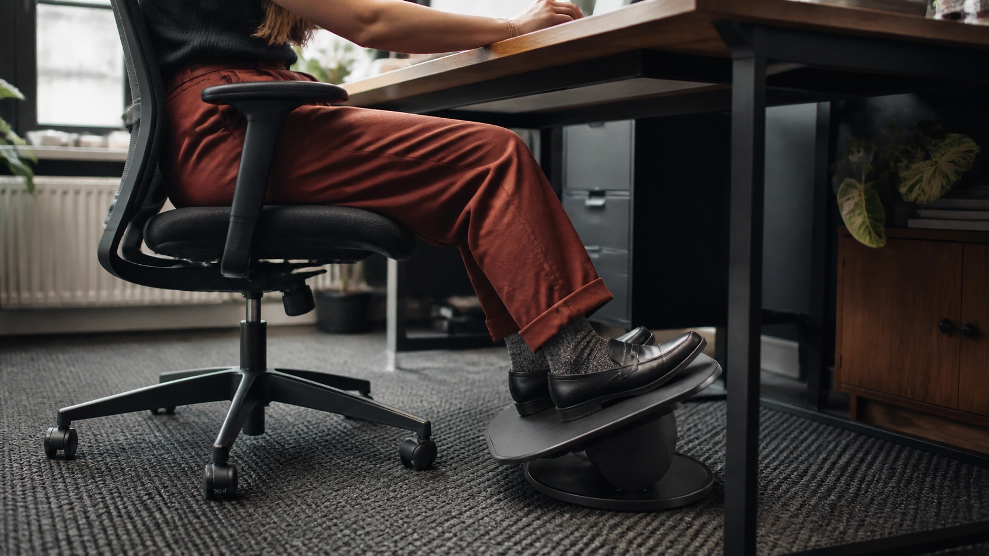 Desk worker changing ankle angle and foot position beneath a home-office desk during focused work