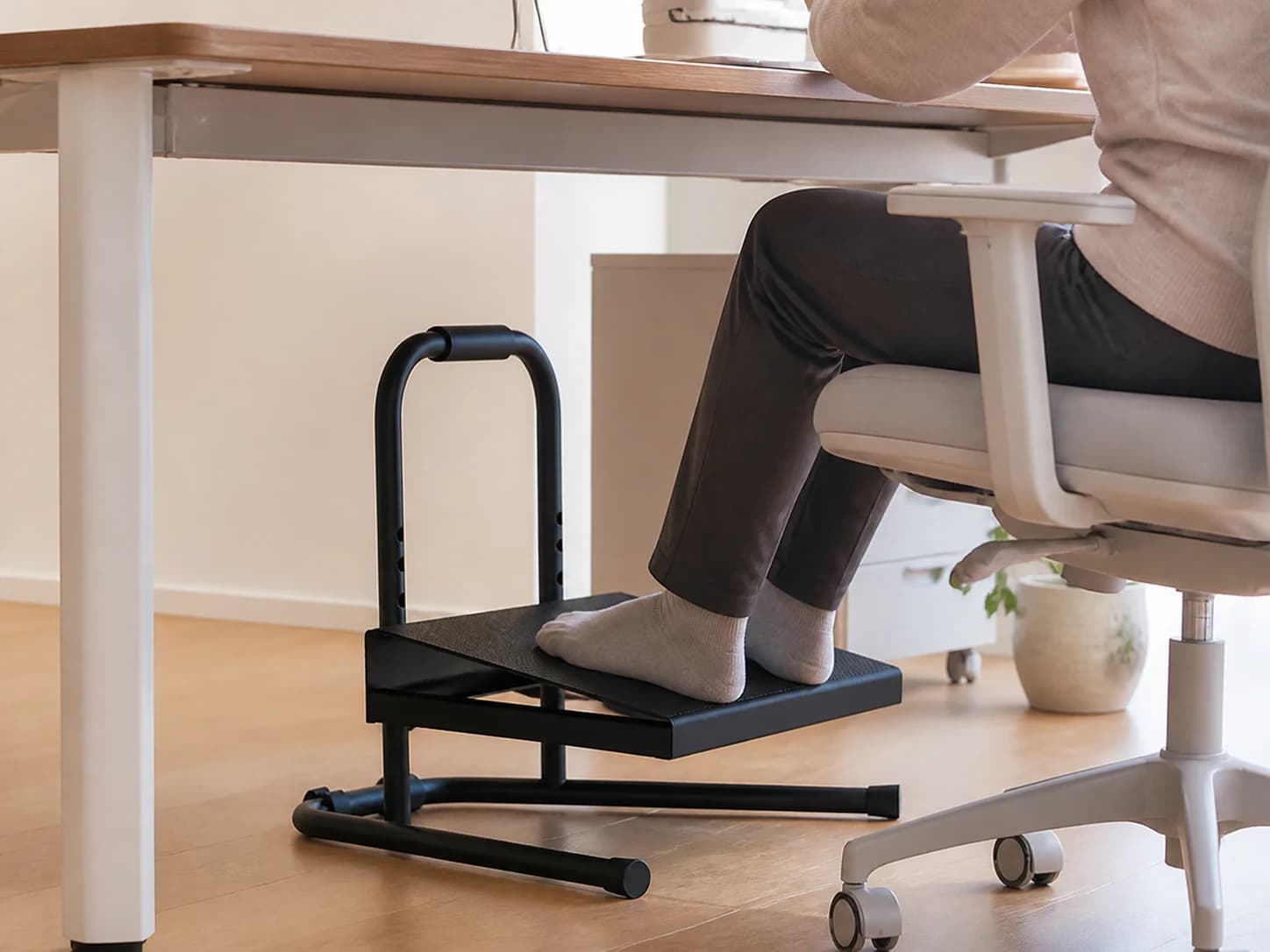 Seated person using RiseRest 6 beneath an office desk
