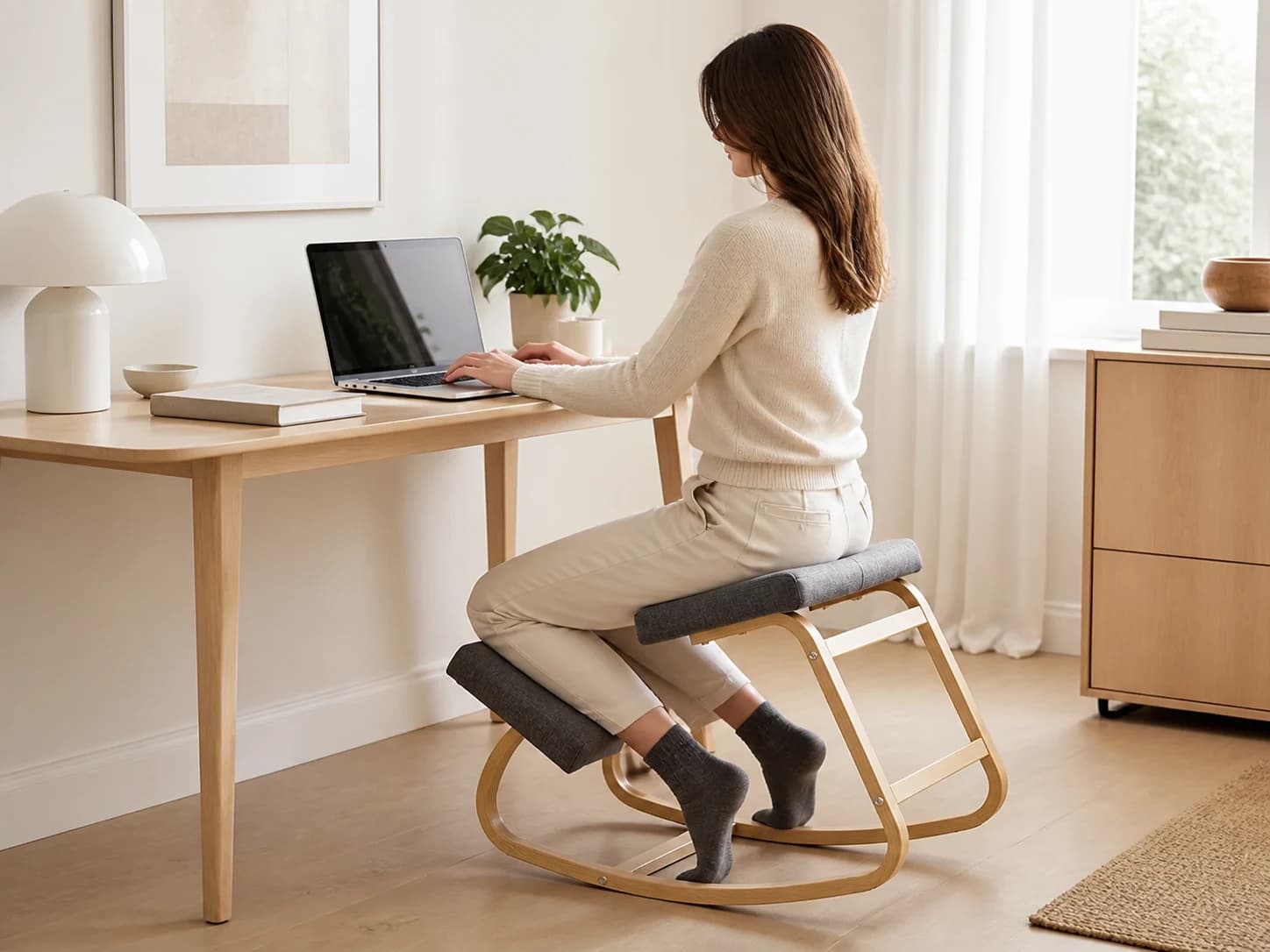 Person seated on the gray KneelArc Chair while working at a desk