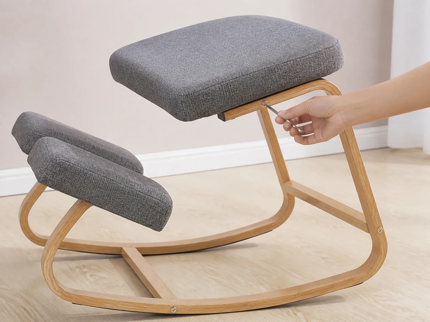 Hand tightening a visible fastener on the KneelArc Chair with a small hex key