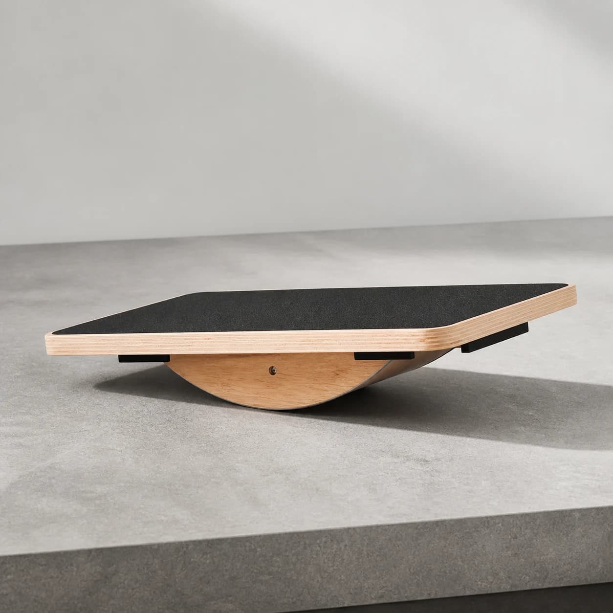 Elevated three-quarter studio view of the PivotArc board and centred curved rocker