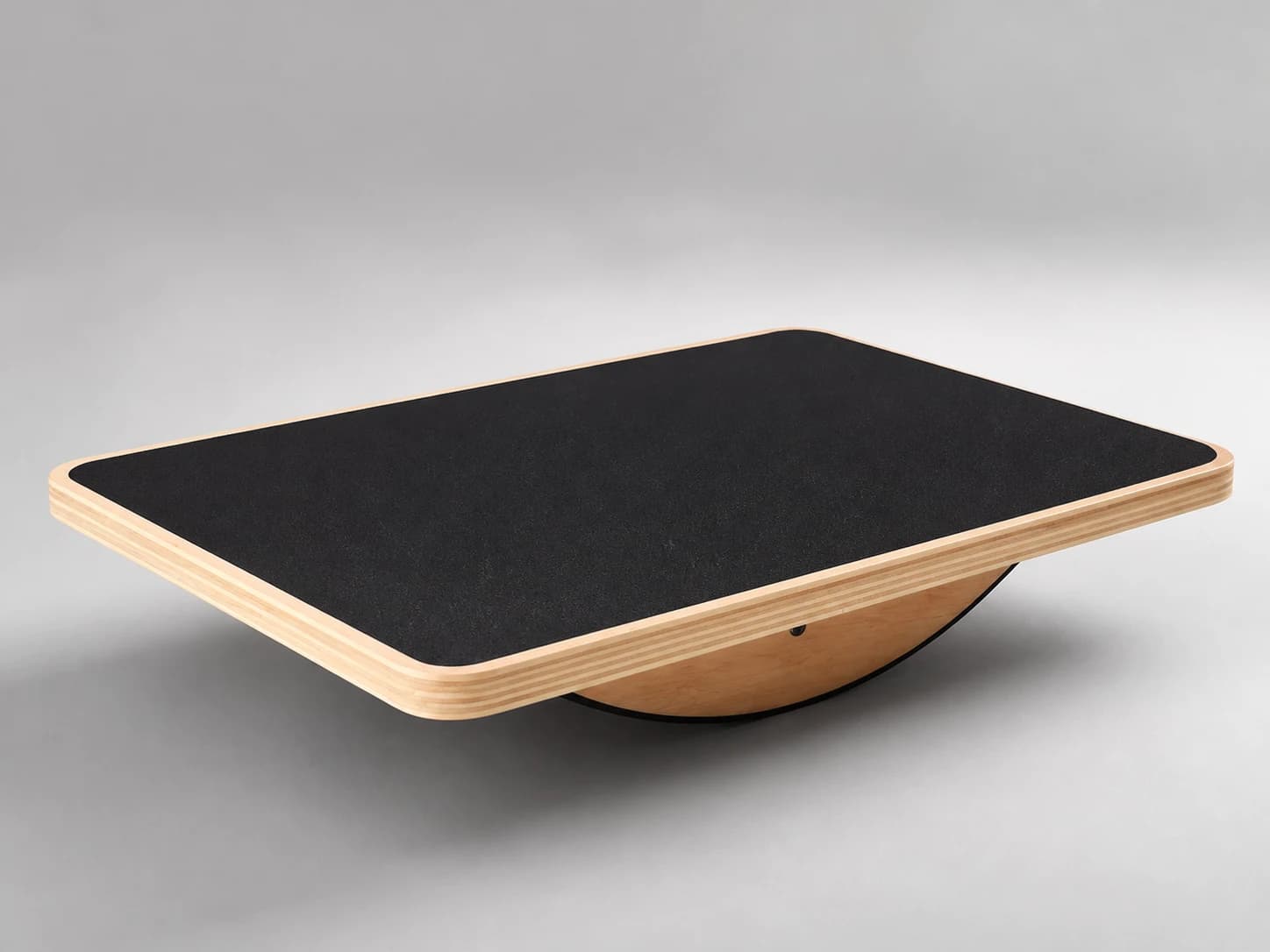 Close studio view of the PivotArc black top/contact surface and layered wooden perimeter
