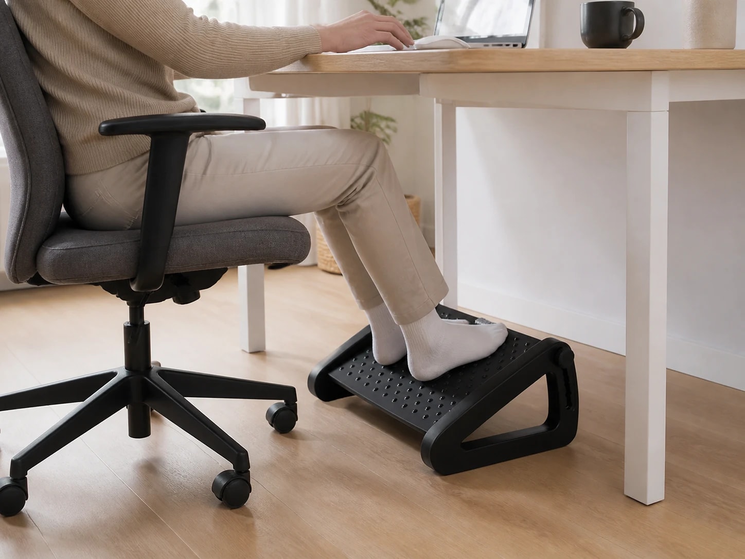 Seated person using the LiftRoll footrest beneath an office desk