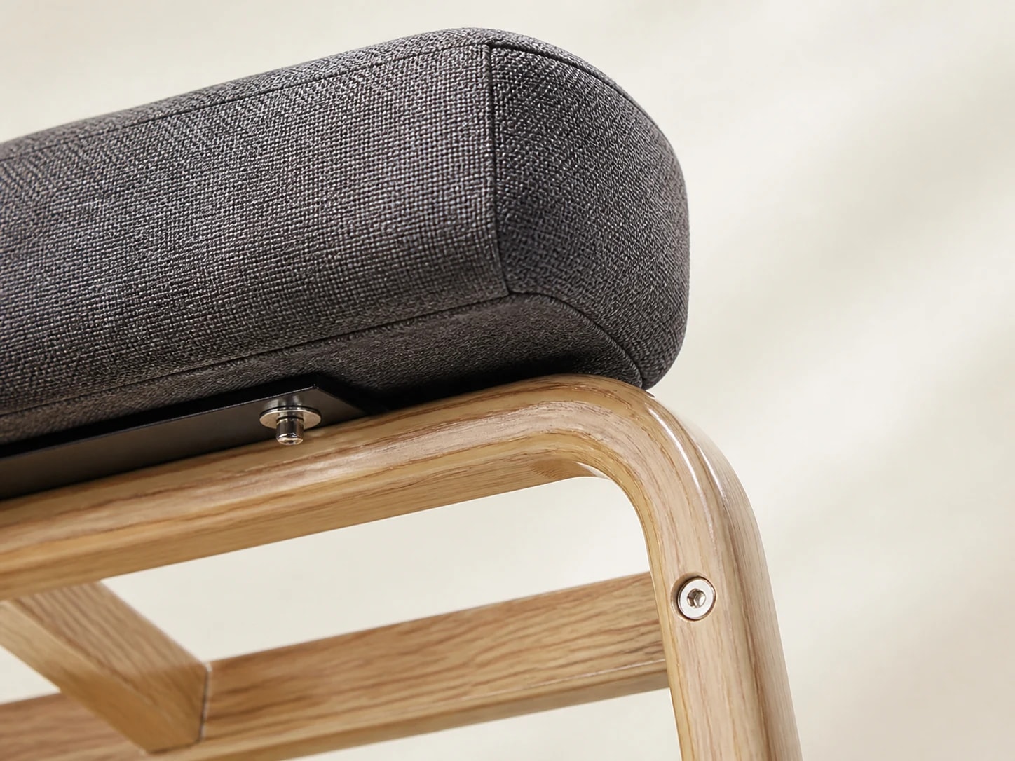 Close-up of the gray seat edge, visible fastener, and wood-grain-finished iron frame