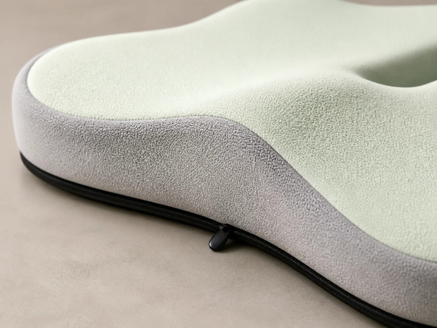 Macro view of SitContour green fabric, gray side panel, black piping, and zipper pull