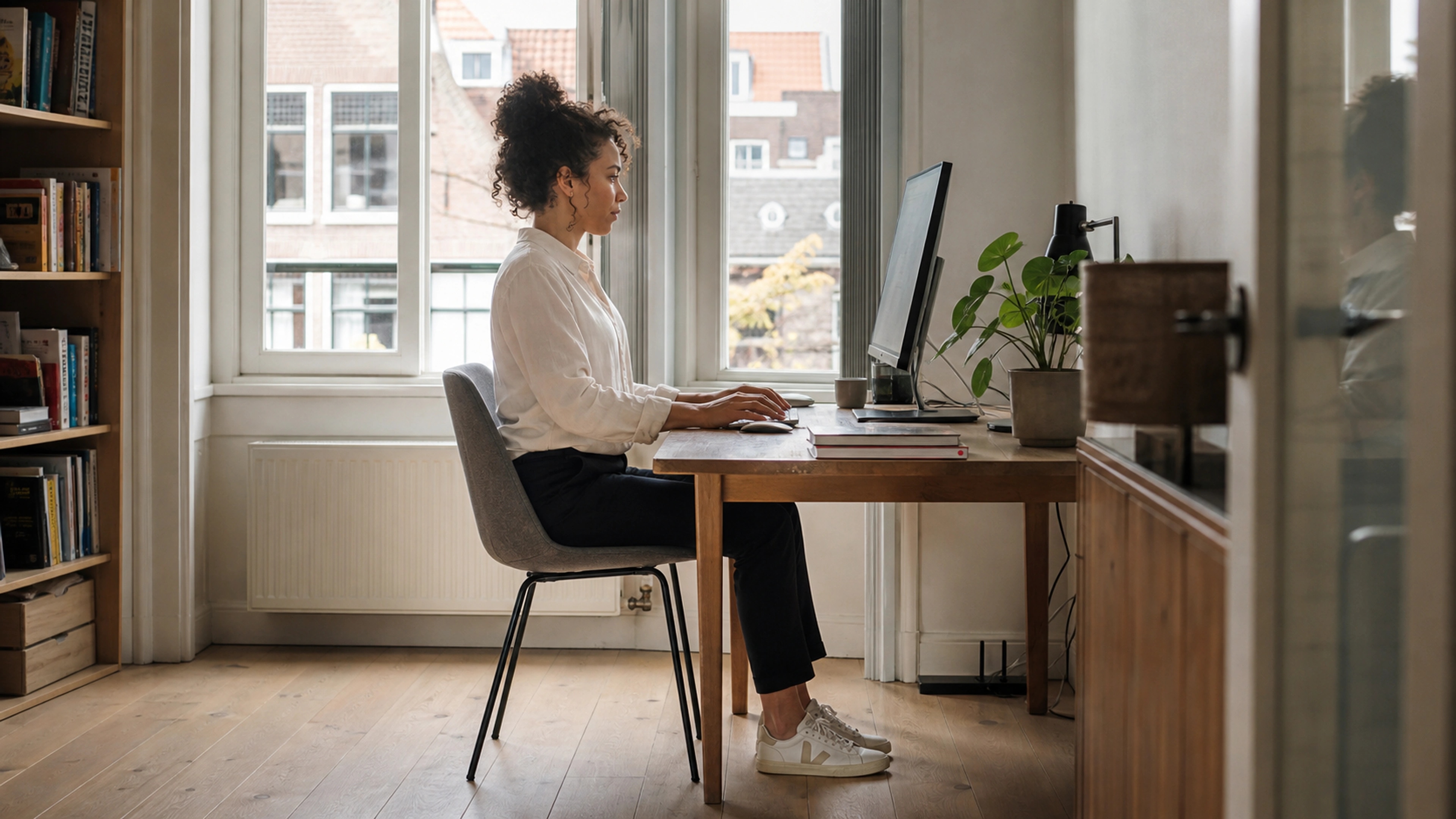 Side view of a woman working with relaxed shoulders, grounded feet, and balanced seated posture