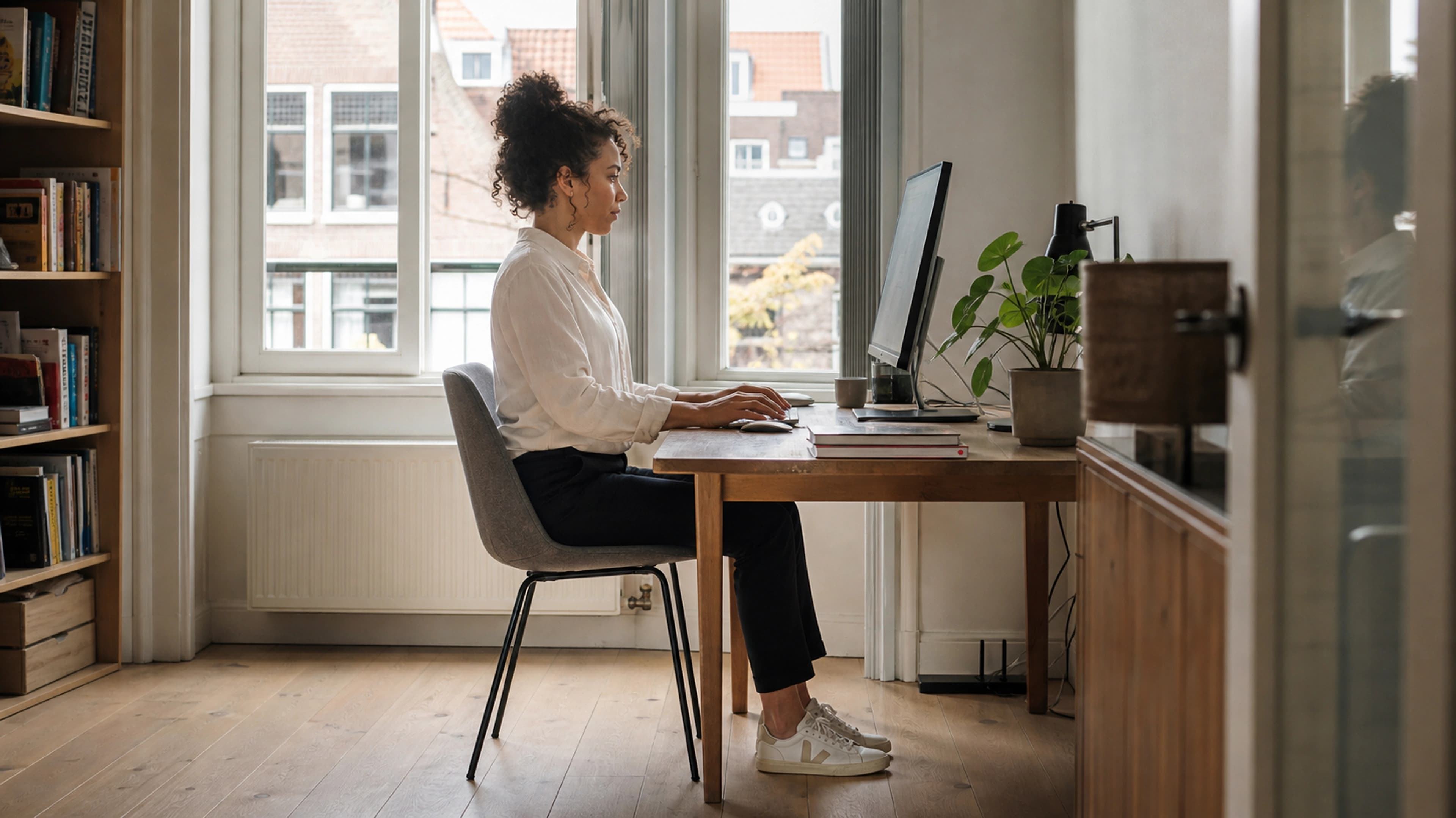 Side view of a woman working with relaxed shoulders, grounded feet, and balanced seated posture