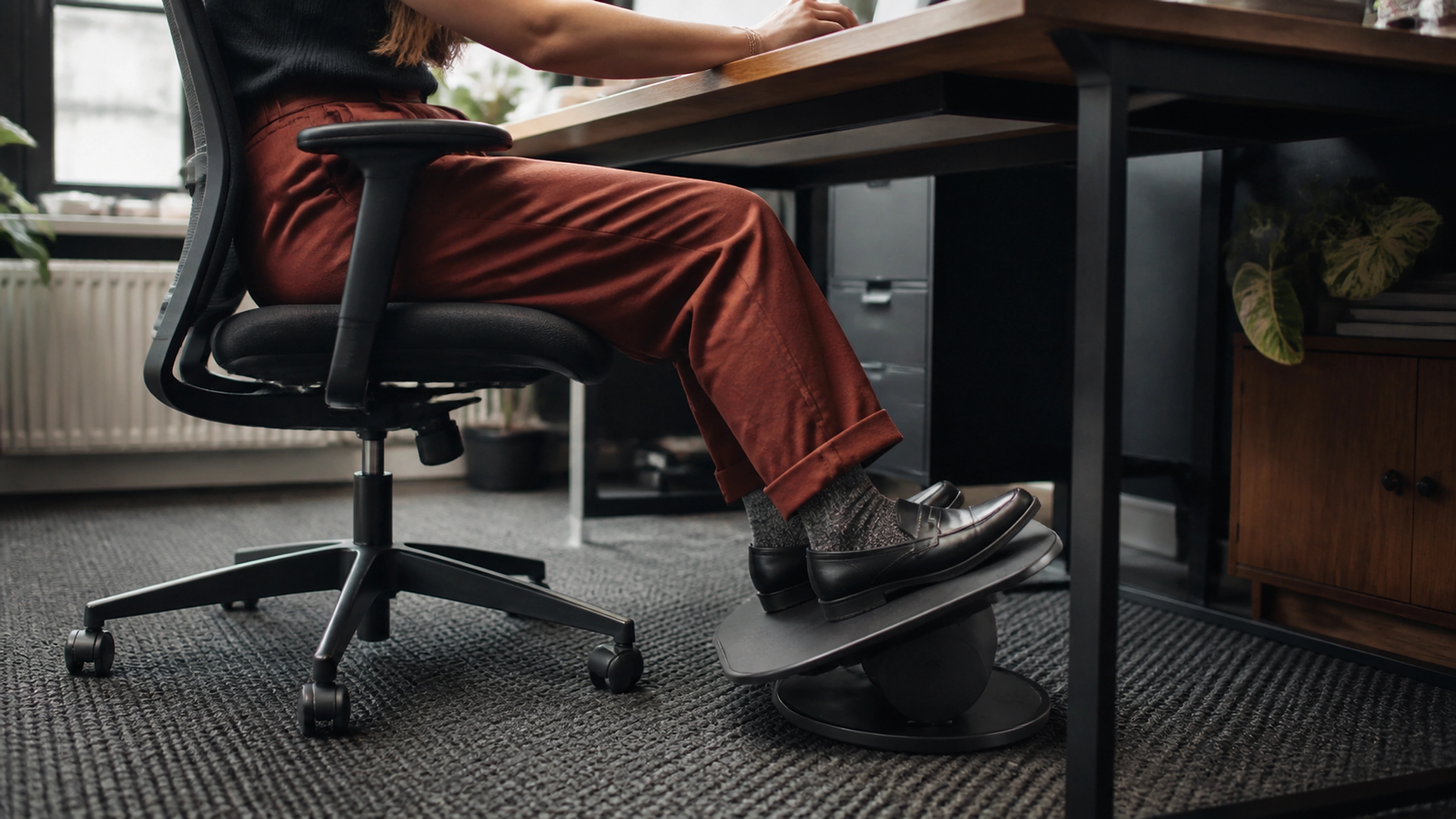 Desk worker changing ankle angle and foot position beneath a home-office desk during focused work