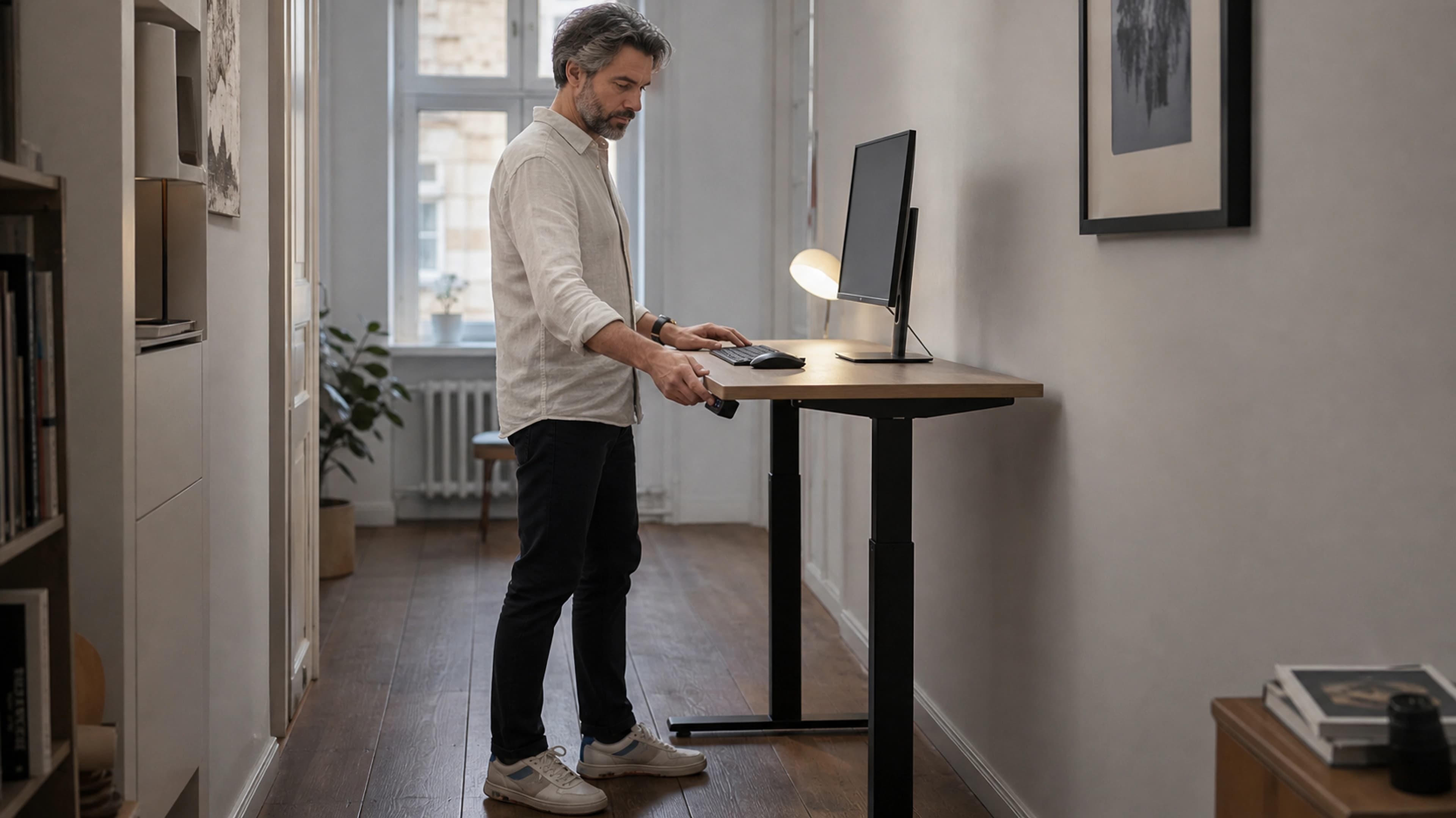 Person testing a compact height-adjustable workstation at standing level in a practical home office